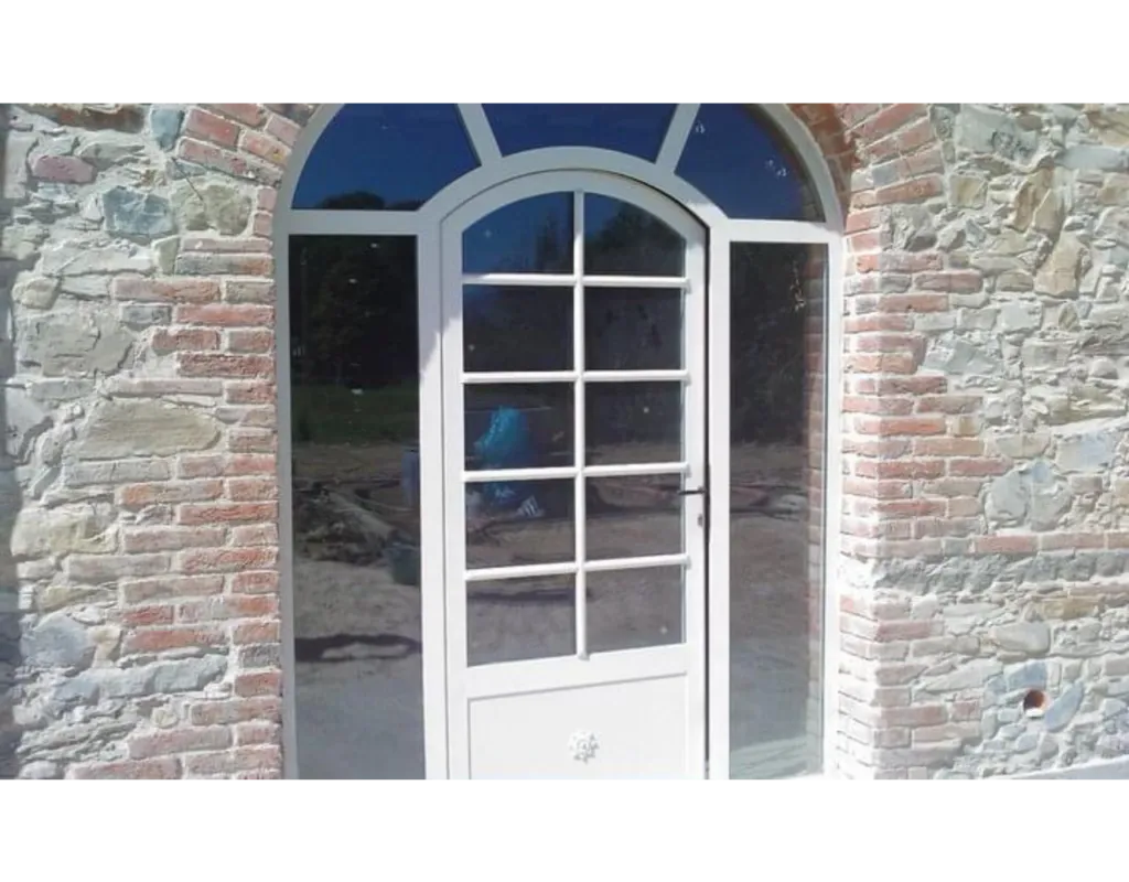 Porta ad arco bianca con sopraluce raggiato su casale in pietra