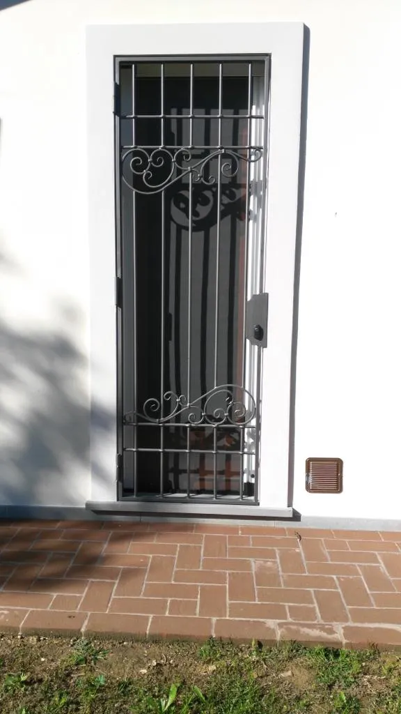 Inferriata grigia con volute decorative su porta d'ingresso